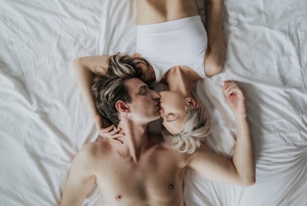 A couple sharing an intimate kiss while lying side by side on a bed.